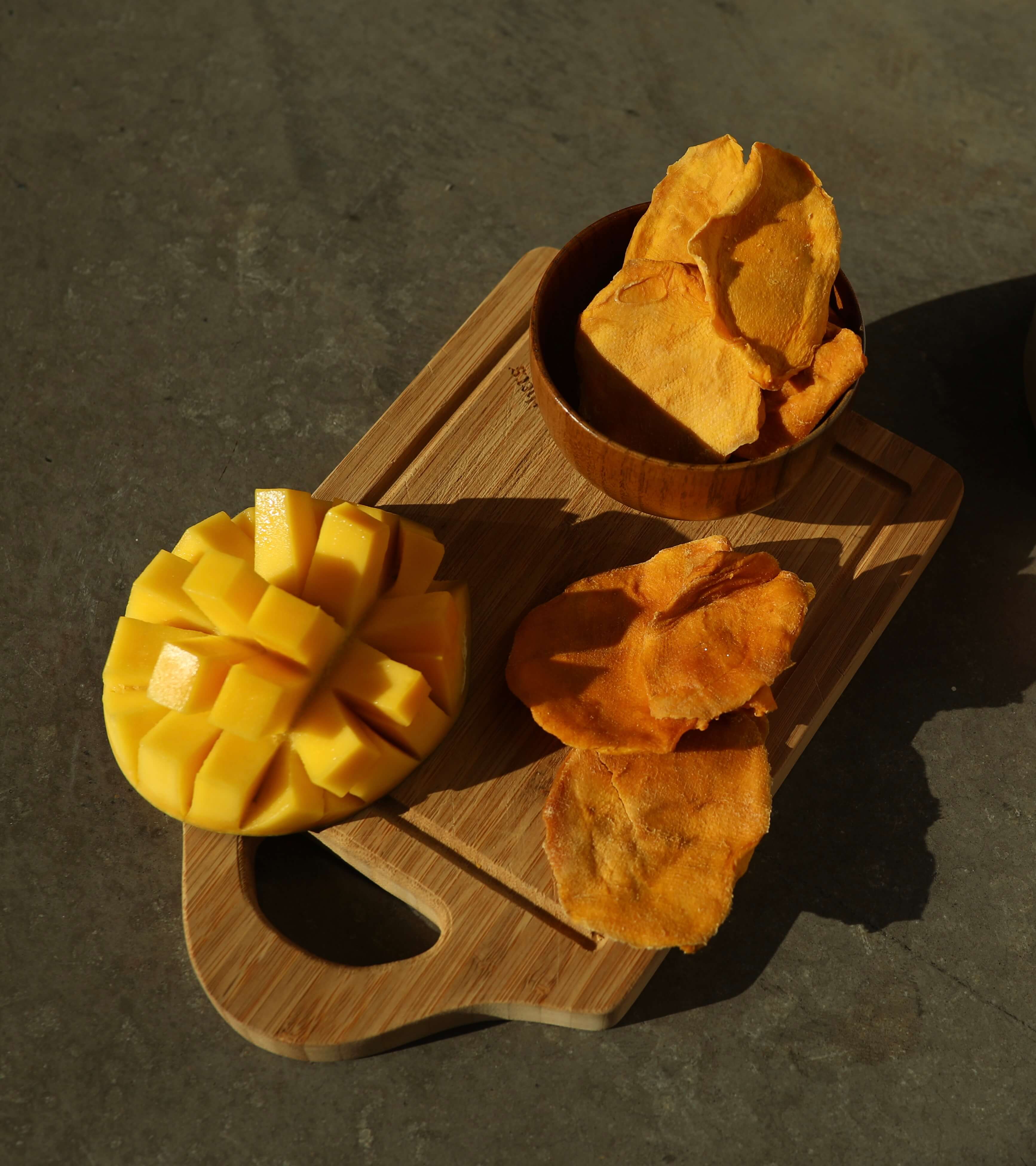 Cut, ripe mango next to dried mango cheeks in a bowl.