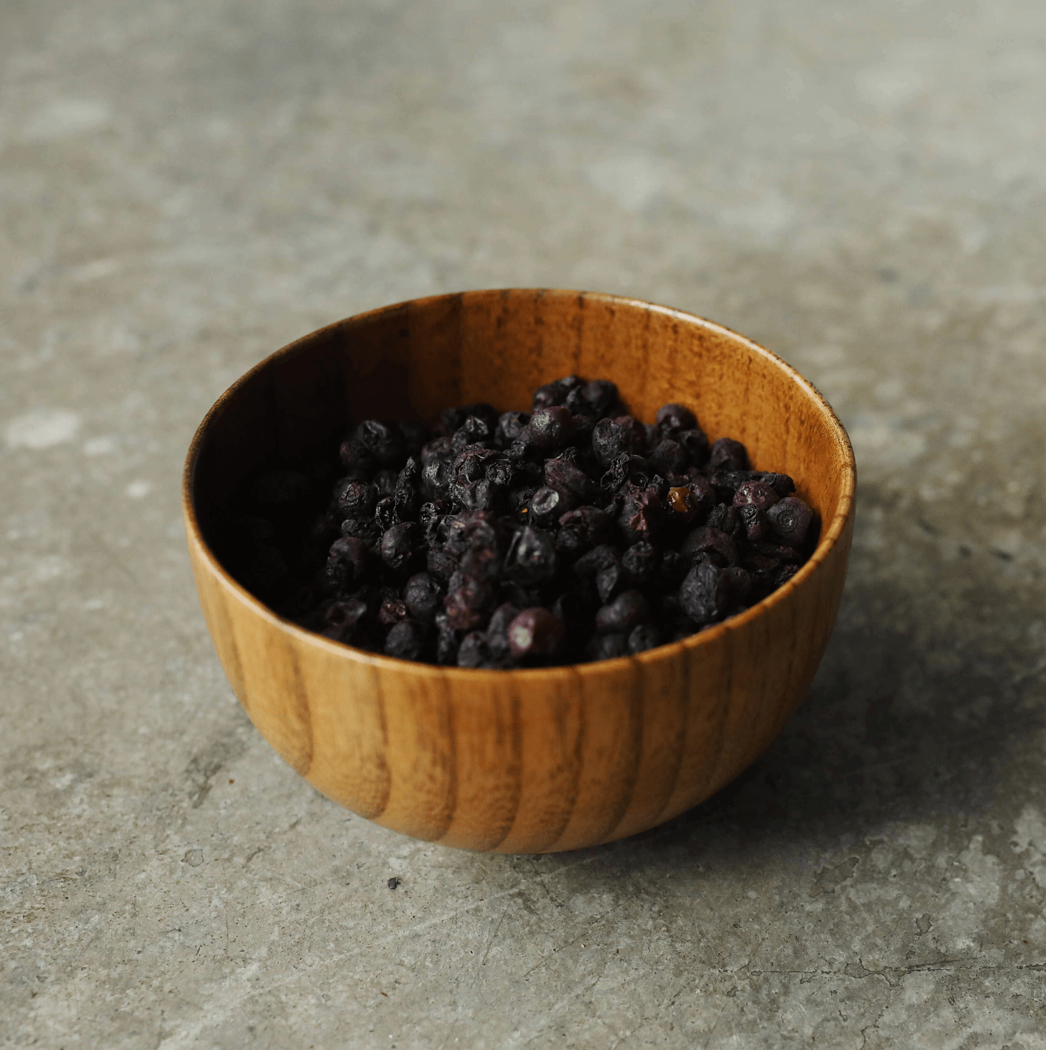 Dried blueberries in a wood bowl.