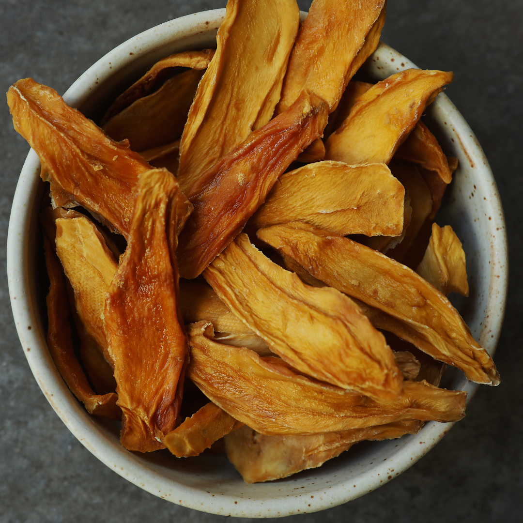 Large bowl of organic dried mango strips in a ceramic bowl.