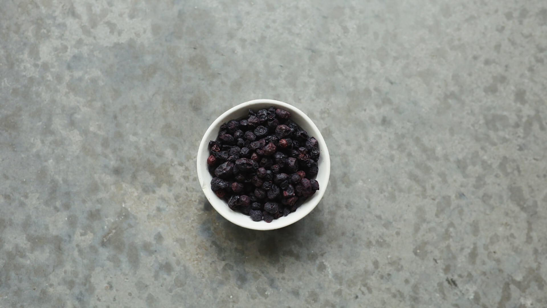 Dried blueberries in a white bowl.